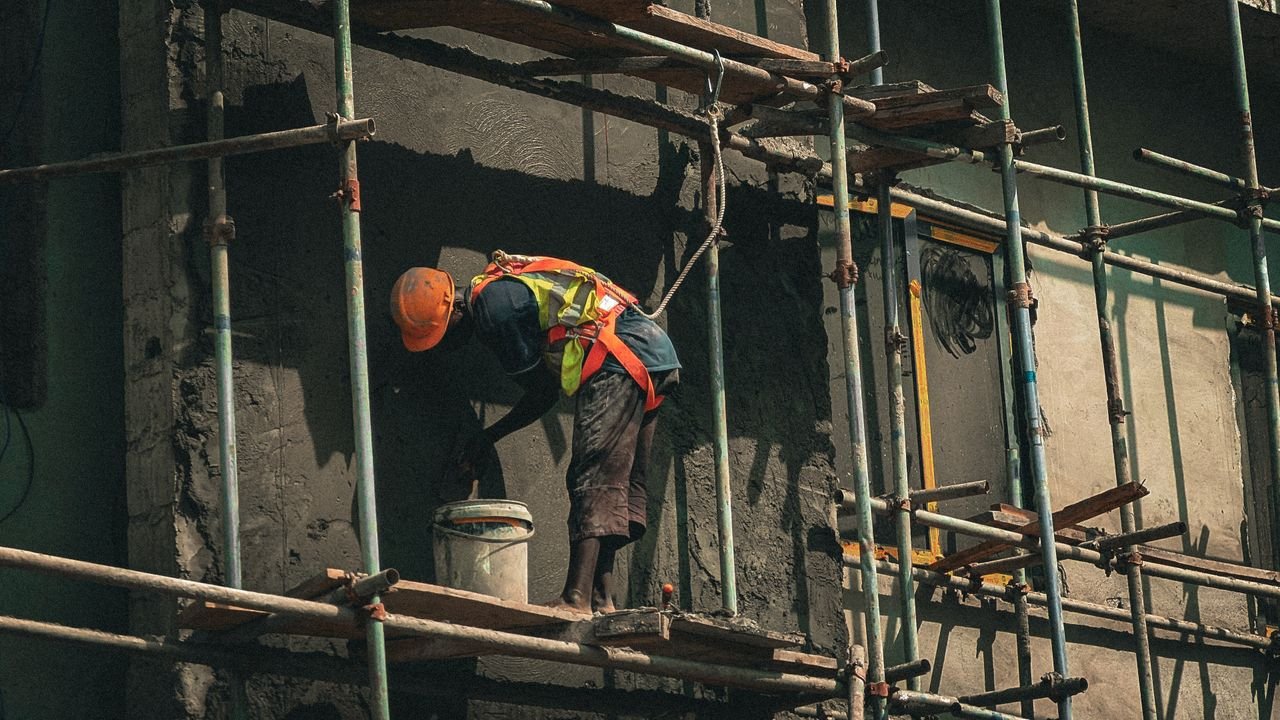 A construction worker applies plaster on a building facade in Abuja, Nigeria.